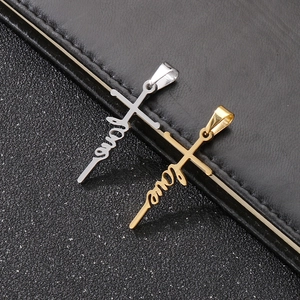 Detailaufnahme von Gold und Silber Kreuzanhängern mit Love Schriftzug auf Leder