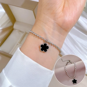 Detail of silver beaded chain bracelet featuring a black four-leaf clover motif pendant