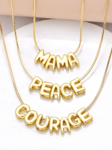 Macro view of gold bubble letter pendants MAMA PEACE and COURAGE on snake chains
