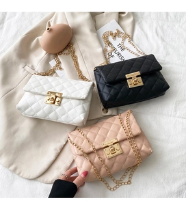 Close-up of quilted chain bags in black, white, and pink with gold metal lock details