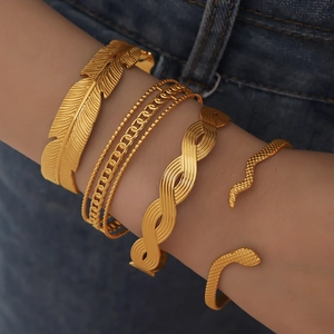Five-piece vintage 18K gold plated Cuban link and feather bangle set worn on a model