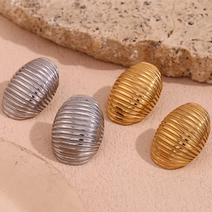 Close-up of gold and silver vintage J-shaped earrings with spiral ribbed textures