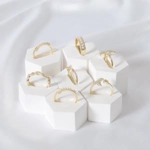 Gold ring set with pearls and zircons displayed on white hexagonal geometric stands