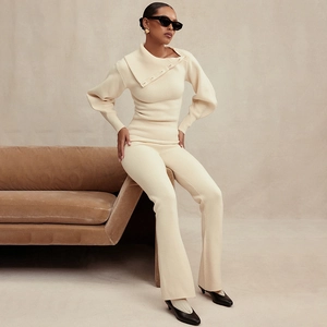Detail view of beige knit two-piece set with off-shoulder top and flared trousers