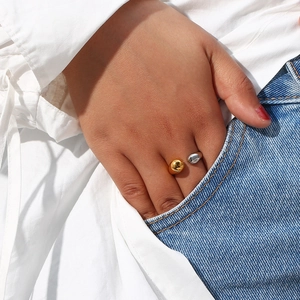 Detail of gold and silver teardrop open rings on finger styled with denim pocket