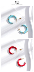 Detail of C-shaped enamel earrings in blue and red with 3D gold hearts and tile display