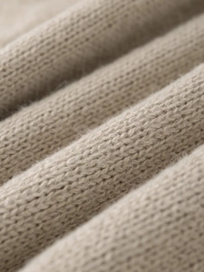 Macro detail of soft beige knit fabric showing high-quality wool texture and weave