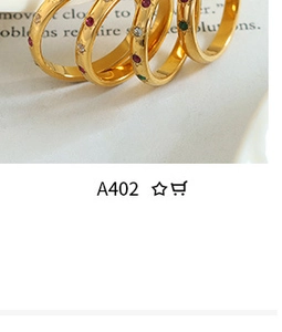Close-up of four minimalist gold stacking rings with colorful red green and white stones