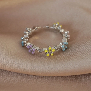 Detailed macro of colorful enamel flowers and zircons on a silver open vine ring