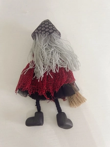 Detail of a handmade Halloween witch doll with grey hair, black pointed hat, and broomstick
