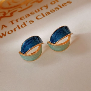 Macro shot of geometric enamel earrings with blue and green drip oil gold trim