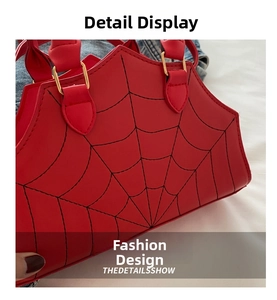 Detail view of red shell bag featuring black spider web embroidery and gold metal hardware