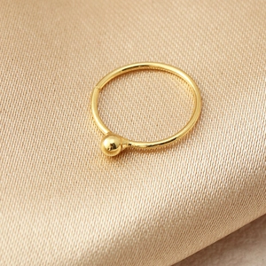 Dettaglio ravvicinato di un anello al naso dorato finto con perla su tessuto dorato