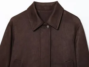 Détail d'une veste en similicuir marron café avec bouton métallique et texture mate