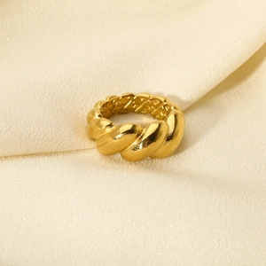 Detailed view of an 18K gold-plated croissant ring on a soft beige silk fabric