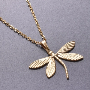 Macro detail of a 18k gold-plated stainless steel dragonfly pendant with textured wings