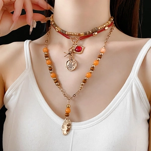 Close-up of multi-layer beaded necklace with red gemstone and vintage gold coin pendant