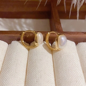 Detail of square pearls set in gold hoop earrings on a professional jewelry display