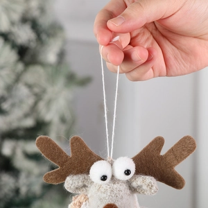 Plush brown reindeer Christmas ornament with antlers hanging on a blurred tree background