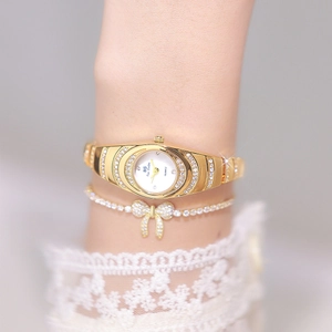 Close-up of luxury gold-tone watch and bow bracelet set with micro-pave rhinestones
