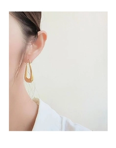 Close-up of a model wearing a gold U-shaped minimalist hoop earring with a polished finish