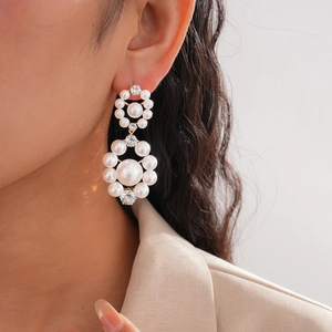Close-up of luxury white pearl and rhinestone hoop earrings on a model in beige blazer