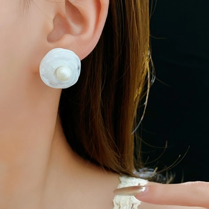Detailed close-up of a white resin flower earring with pearl center on model ear