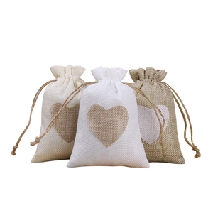 Three natural linen drawstring jewelry pouches with heart patterns in varied colors