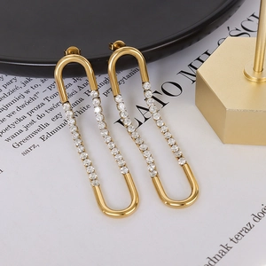 French style gold U-shaped earrings with sparkling zircons set on a book background