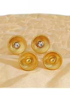 Detail of gold titanium steel earrings with radial texture and zircon inlays on fabric