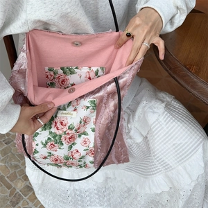 Detail of pink velvet tote bag featuring red rose floral lining and magnetic closure