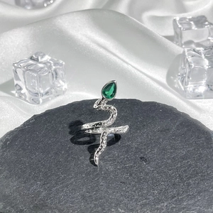 Detailed shot of silver snake ring with green teardrop gem and realistic scale texture