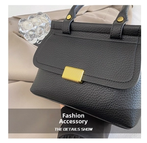 Détail du sac en cuir litchi noir avec fermoir métallique doré et finitions chic
