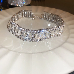 Close-up of three-row rhinestone choker necklace on white ceramic tray with starburst shine