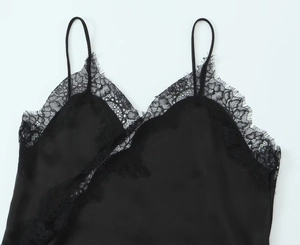 Close-up of black silk dress featuring delicate floral lace trim and spaghetti straps