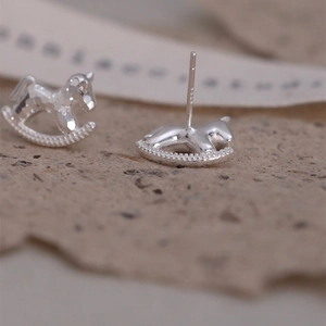 Macro shot of silver rocking horse studs showing S925 hallmark and texture details