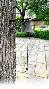 Macro shot of cast iron decorative doorbell mounted on tree trunk in rustic garden