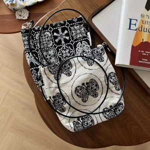Détail d'un sac en toile brodé vintage montrant des motifs floraux et une étiquette en tissu