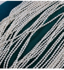 Macro detail of 2.5mm natural white freshwater seed pearls on dark green velvet