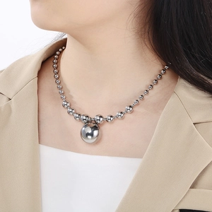 Detailed view of silver hollow ball pendant necklace worn by model on neck