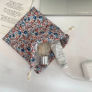 Close-up of floral drawstring pouch showing textured cotton fabric and skincare storage