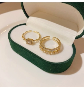 Detail of two gold-plated double-layer rings with zircon stones in a green velvet box