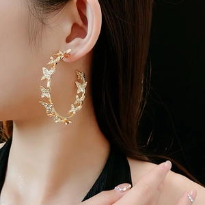 Gros plan sur les créoles dorées papillon avec strass portées de profil par un mannequin