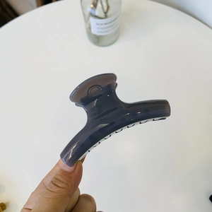 Detail of a dark gray translucent resin hair claw clip with a sleek streamlined design