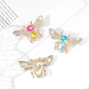 Detailed macro view of crystal-encrusted honey bee brooches with pearls and gold-plated finish