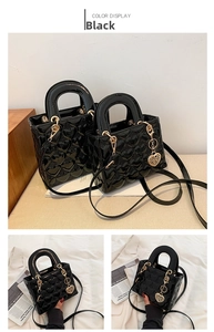 Macro view of black heart-quilted patent leather handbag with gold heart charm