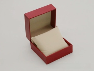 Macro shot of red faux leather watch box with textured finish and soft cream cushion