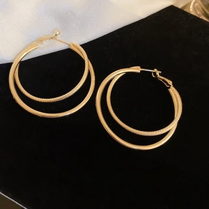 Macro shot of gold double-circle earrings showing S925 silver needle detail and texture