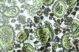 Macro view of green floral paisley pattern on textured white seersucker fabric
