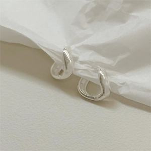 Détail de boucles d'oreilles en argent S925 avec texture de métal liquide sur papier blanc